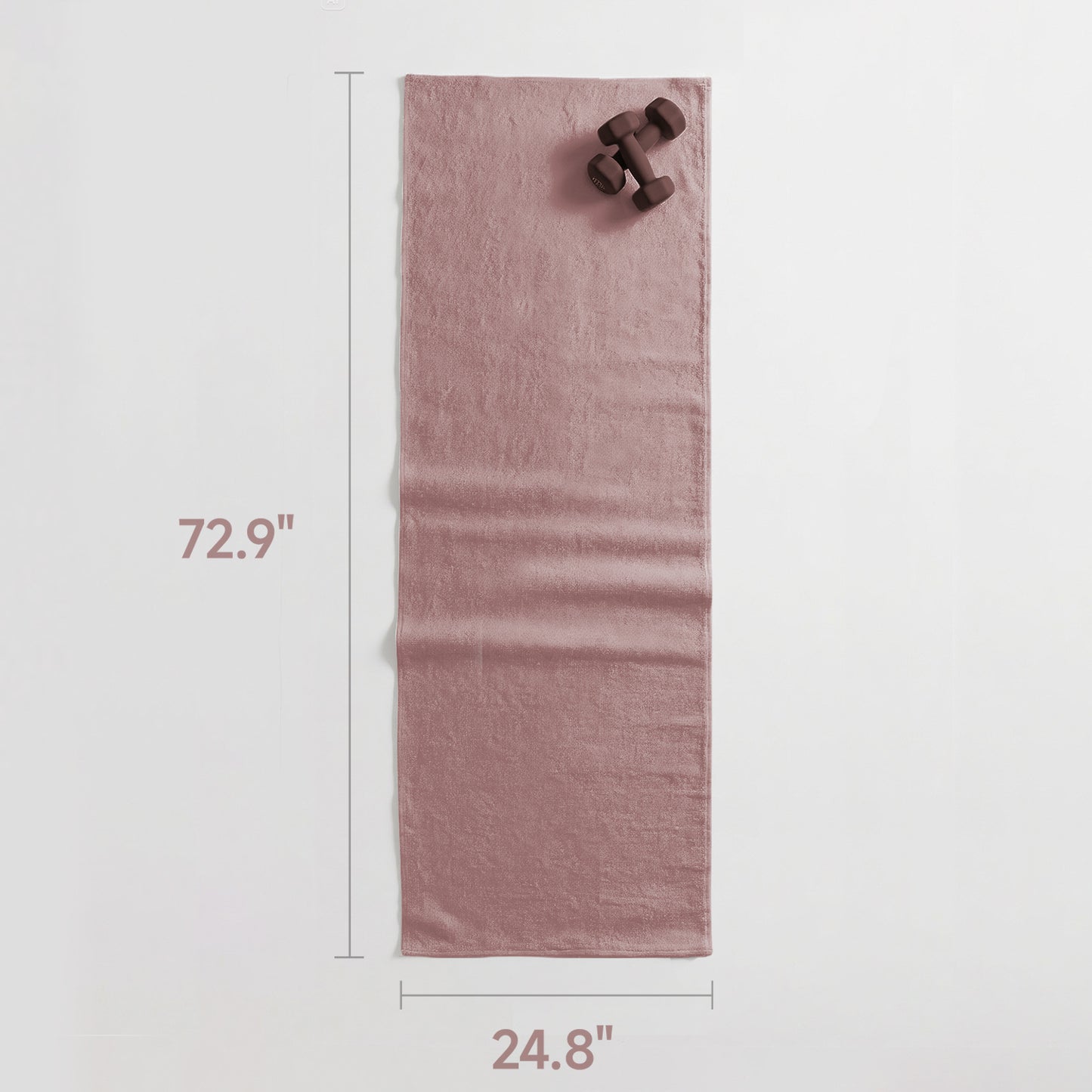 Pink towel with dimensions and dumbbells on a light gray background